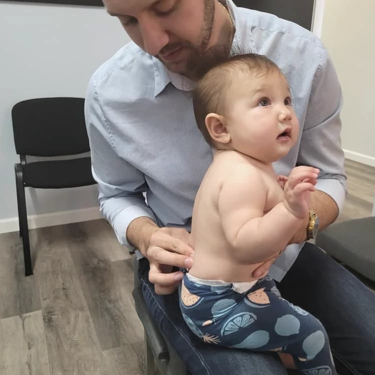 Dr. Ryan Nichols gently checking an infant during a family visit